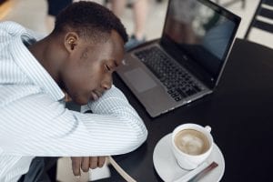 Businessman with laptop sleeping in office cafe