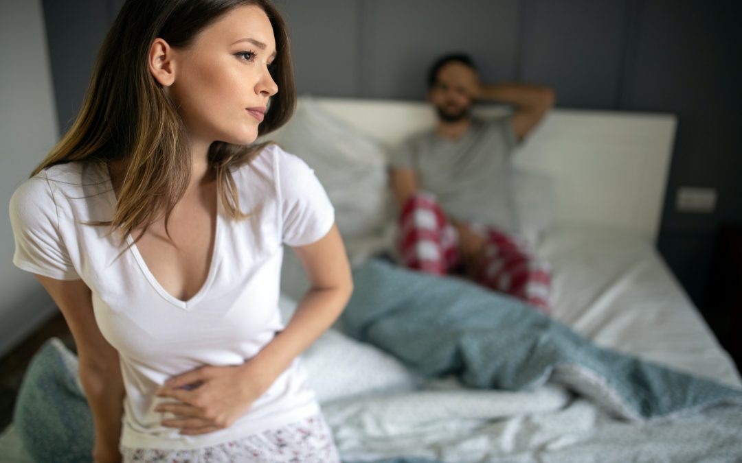 man in bed and woman holding stomach